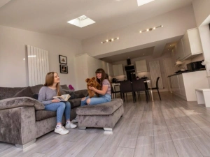 Young woman walking towards sister sitting down in the kitchen